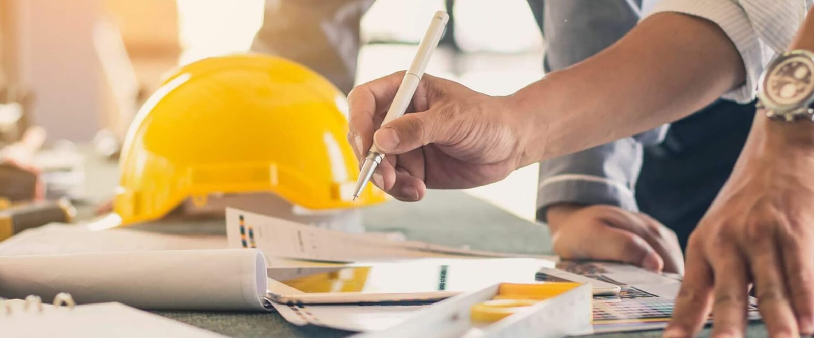 two engineering professionals collaborate over plans at a job site, with the focus only on their hands