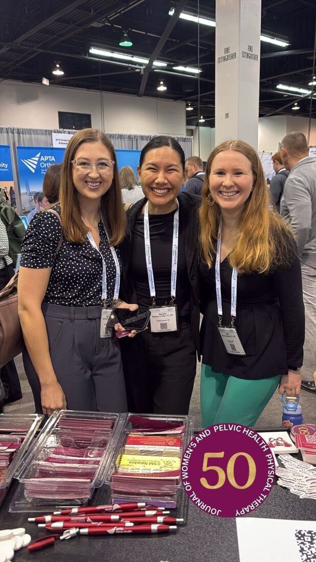 Three people connecting at the Academy booth beside Academy resources