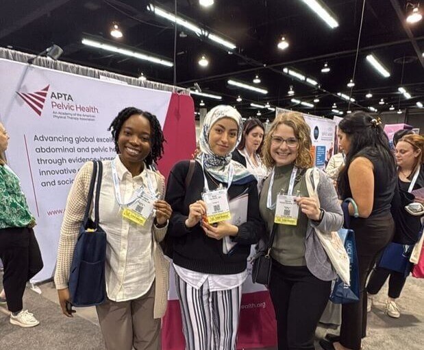 Three attendees smiling in front of the APTA Pelvic Health booth