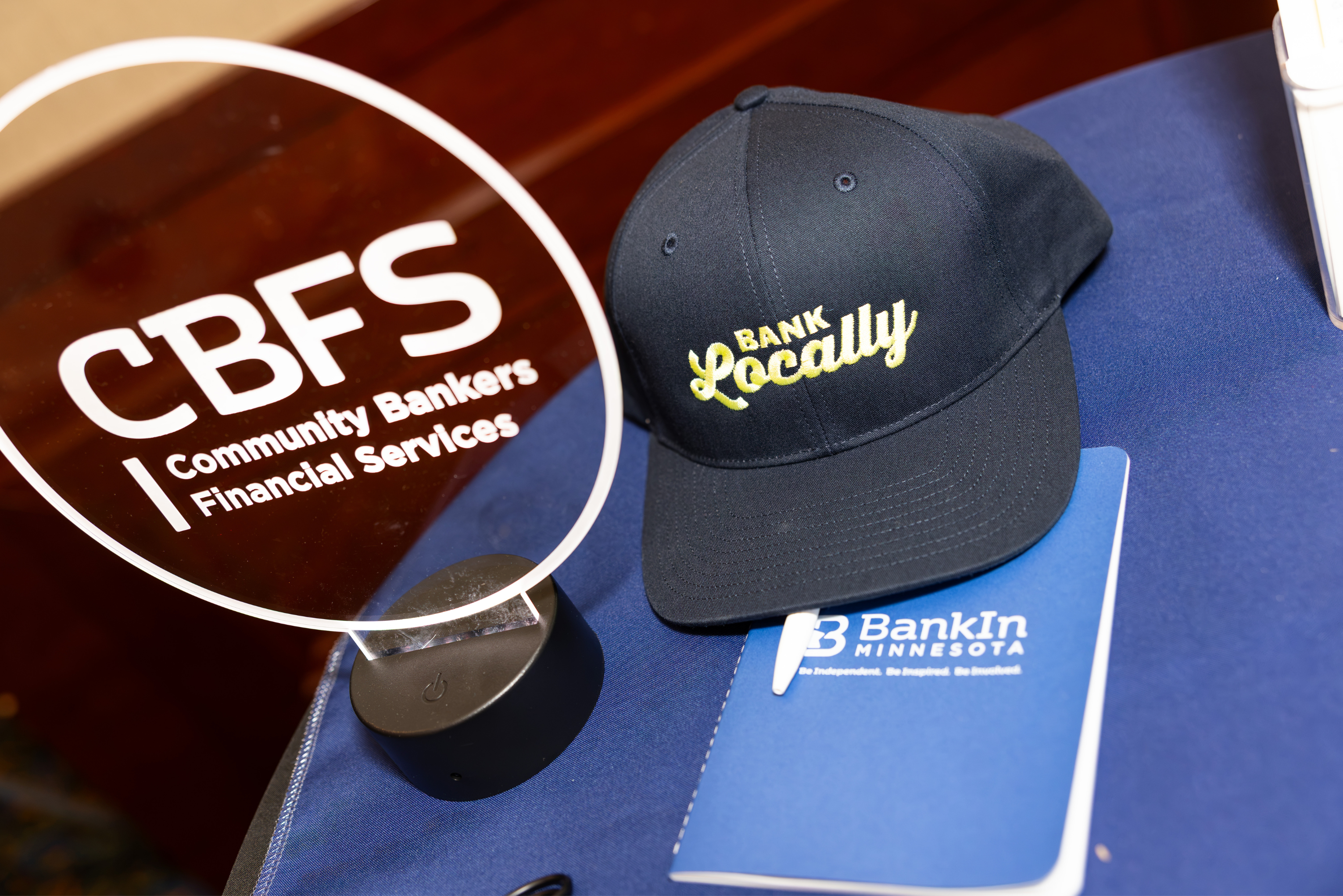 CBFS signage and a Bank Locally hat at a BankIn Minnesota event