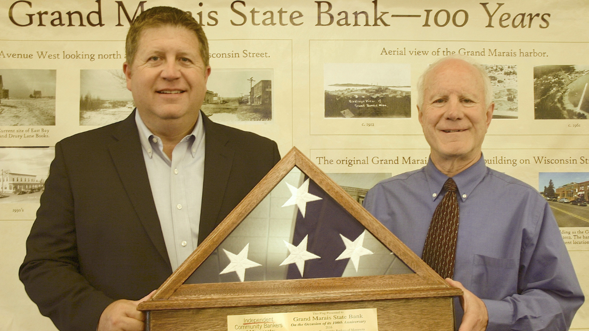 Grand Marais State Bank receives a milestone flag recognizing its 100th anniversary.