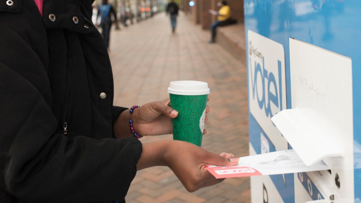 A voter dropping a ballot into a ballot box