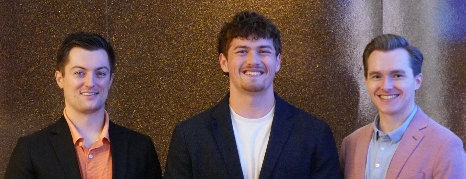 Three Chamber team members in front of the event backdrop