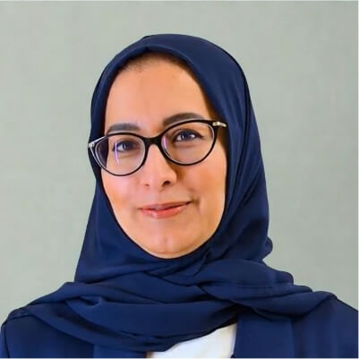 The image depicts a person wearing a traditional black hijab and a white blouse.AI-generated content may be incorrect.