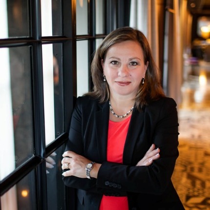 The image depicts a person standing in a well-lit, modern restaurant with a decorative, patterned floor and large windows.AI-generated content may be incorrect.