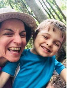 Photo of presenter, Mel Houser, with her child, both smiling outdoors