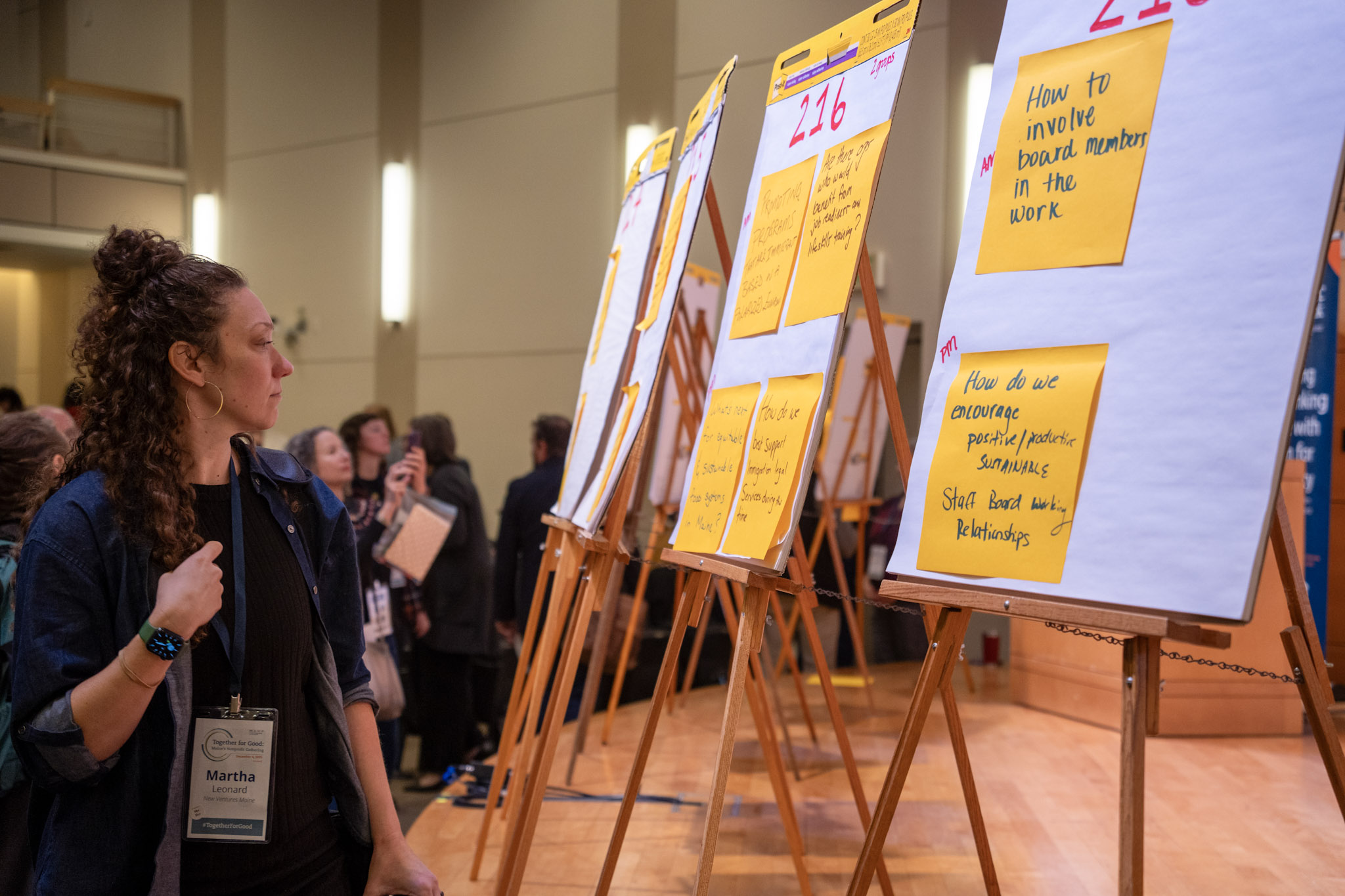 An event participant standing next to four flip chart easels, reading the audience-created discussion topics placed on them with sticky notes.