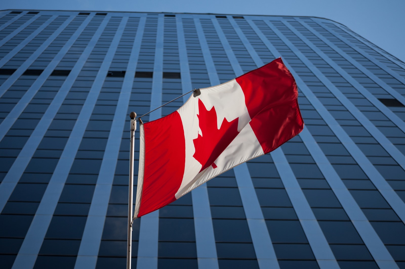 Canadian flag standing in front of a modern office building