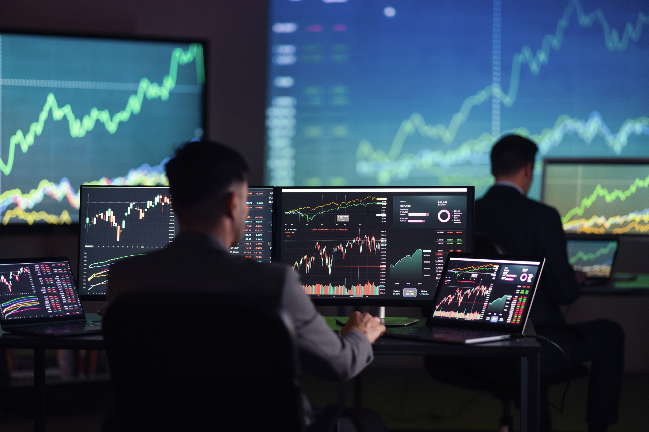A financial analyst sitting in front of computer screens displaying financial data