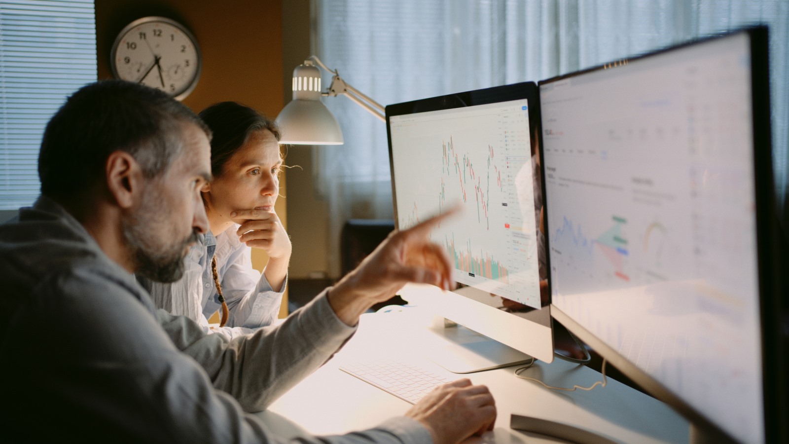Retirement plan professionals analyzing investment data on computer monitors