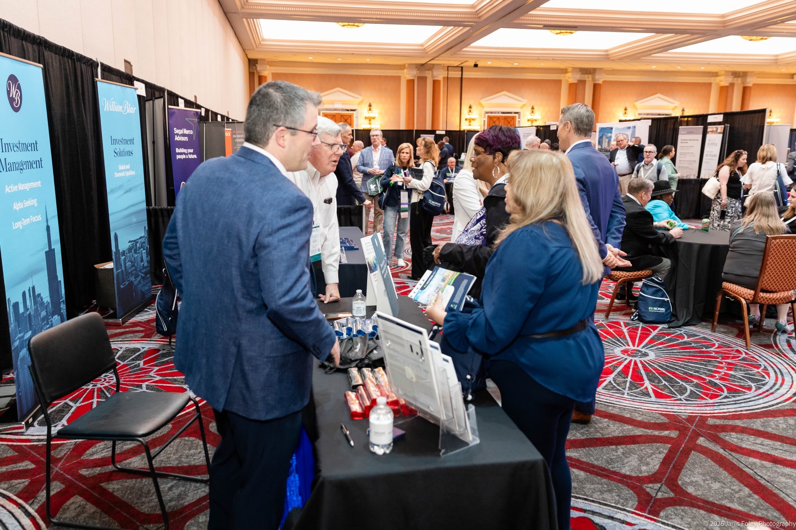 Candid photo of participants smiling while speaking with exhibitors