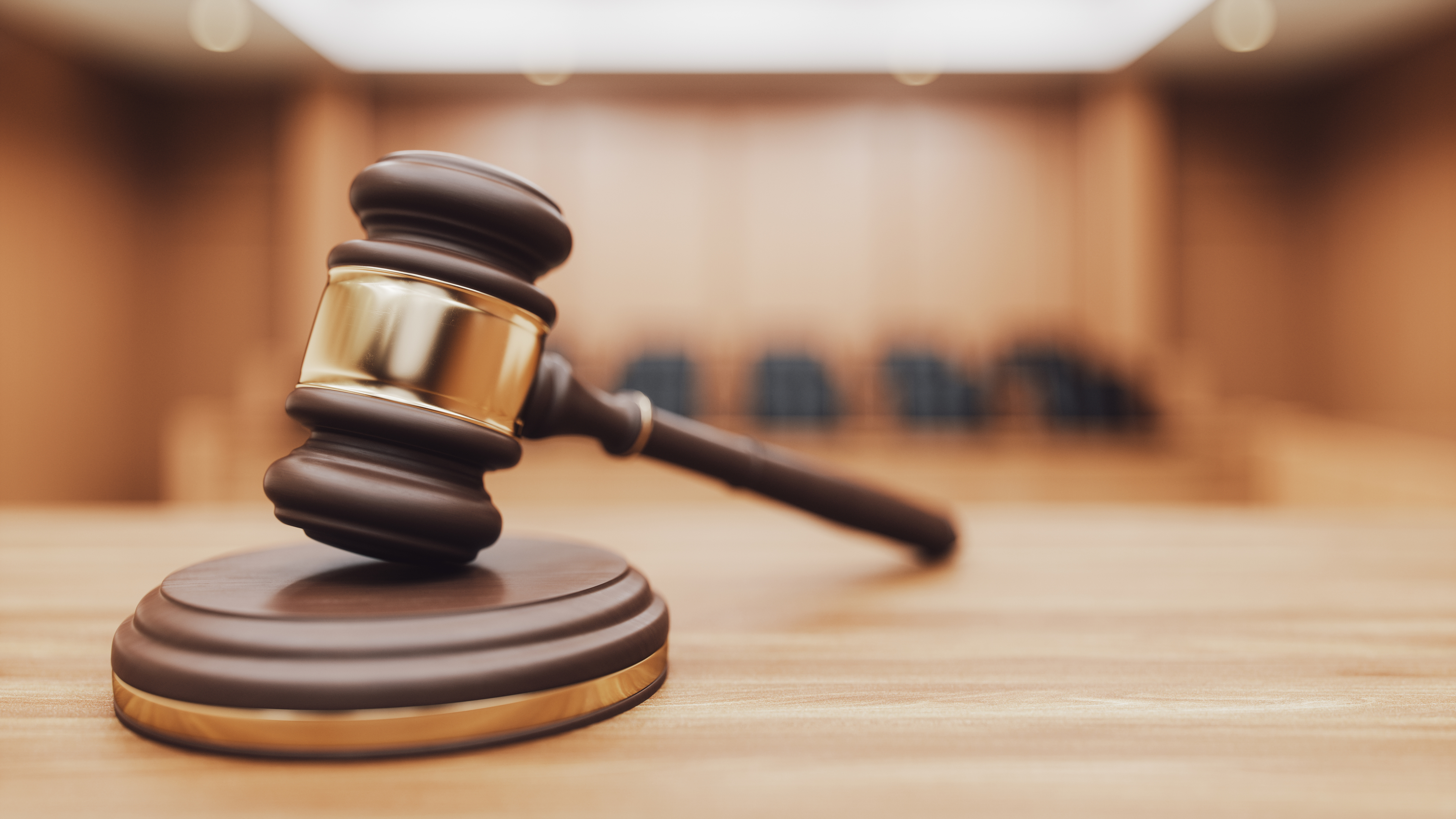 A legal gavel standing front of a blurred courtroom.