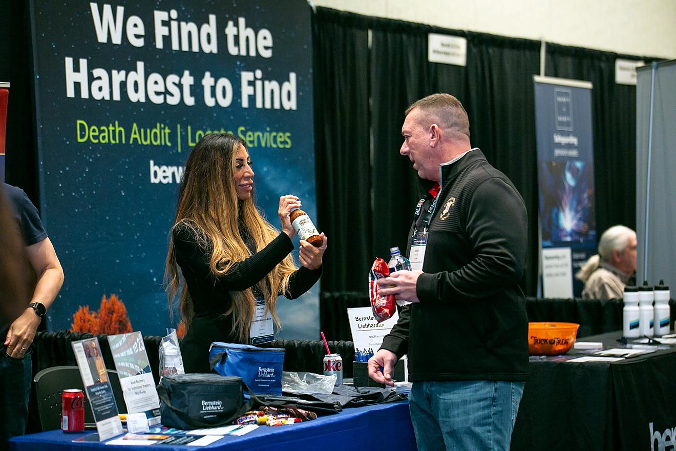 An exhibitor at their booth speaking with an attendee