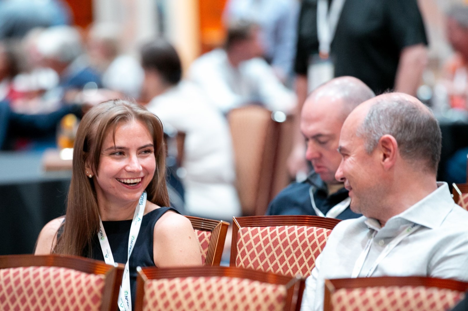 Candid of two attendees smiling at each other in the audience of a presentation