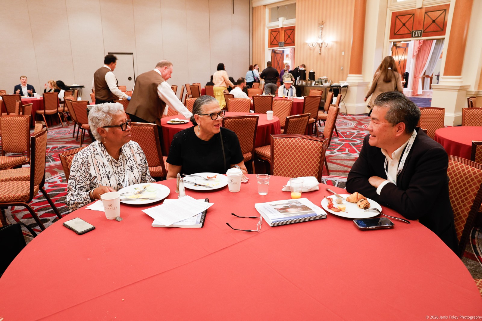 Group photo of three attendees smiling around a circular table
