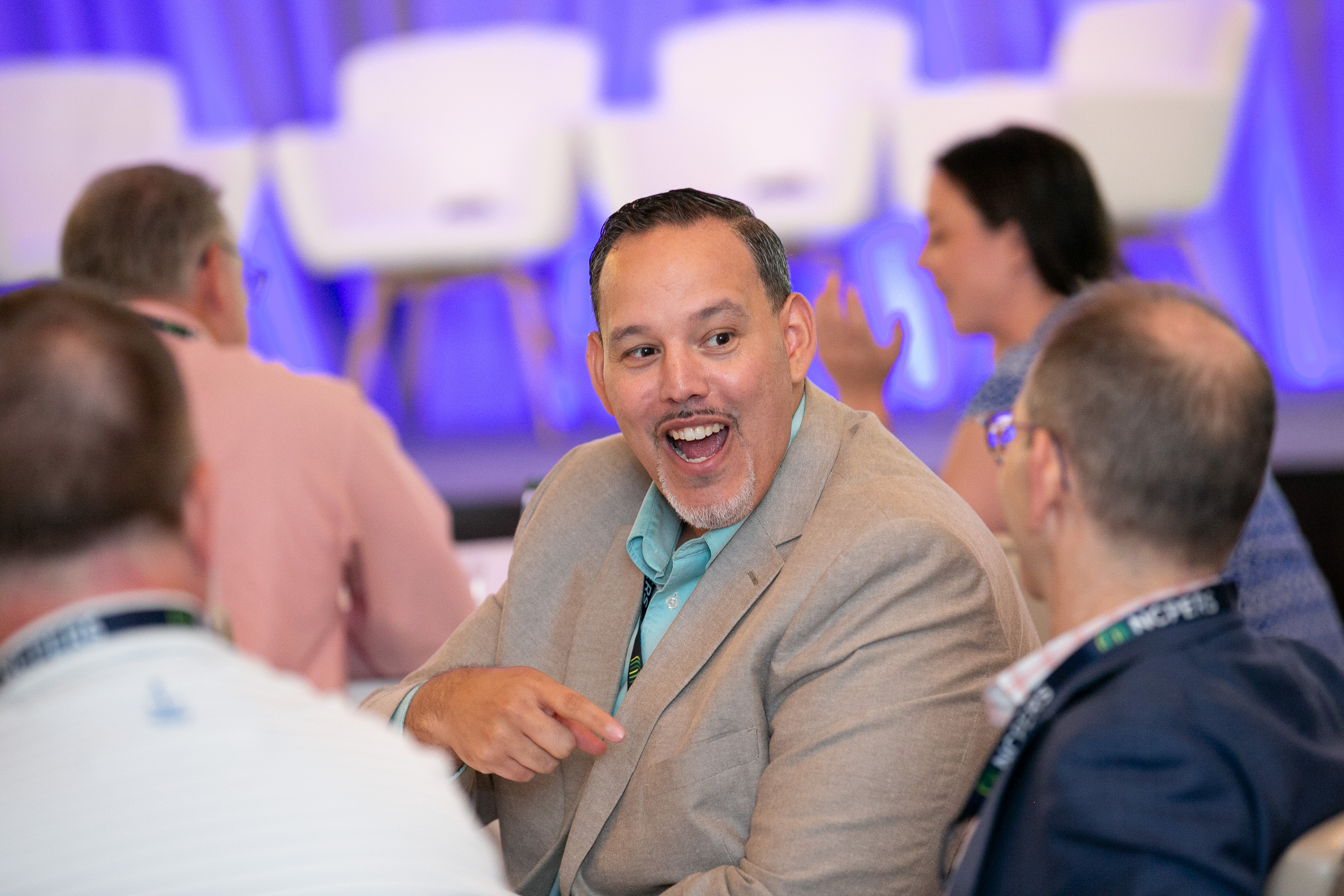 Close shot of an attendee at a table smiling as they interact with another attendee to their left
