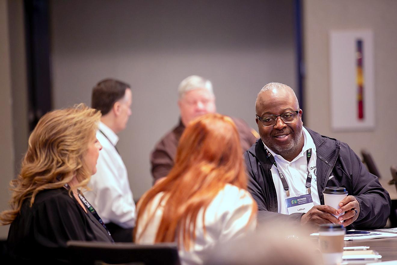 Three attendees talking and smiling around a table