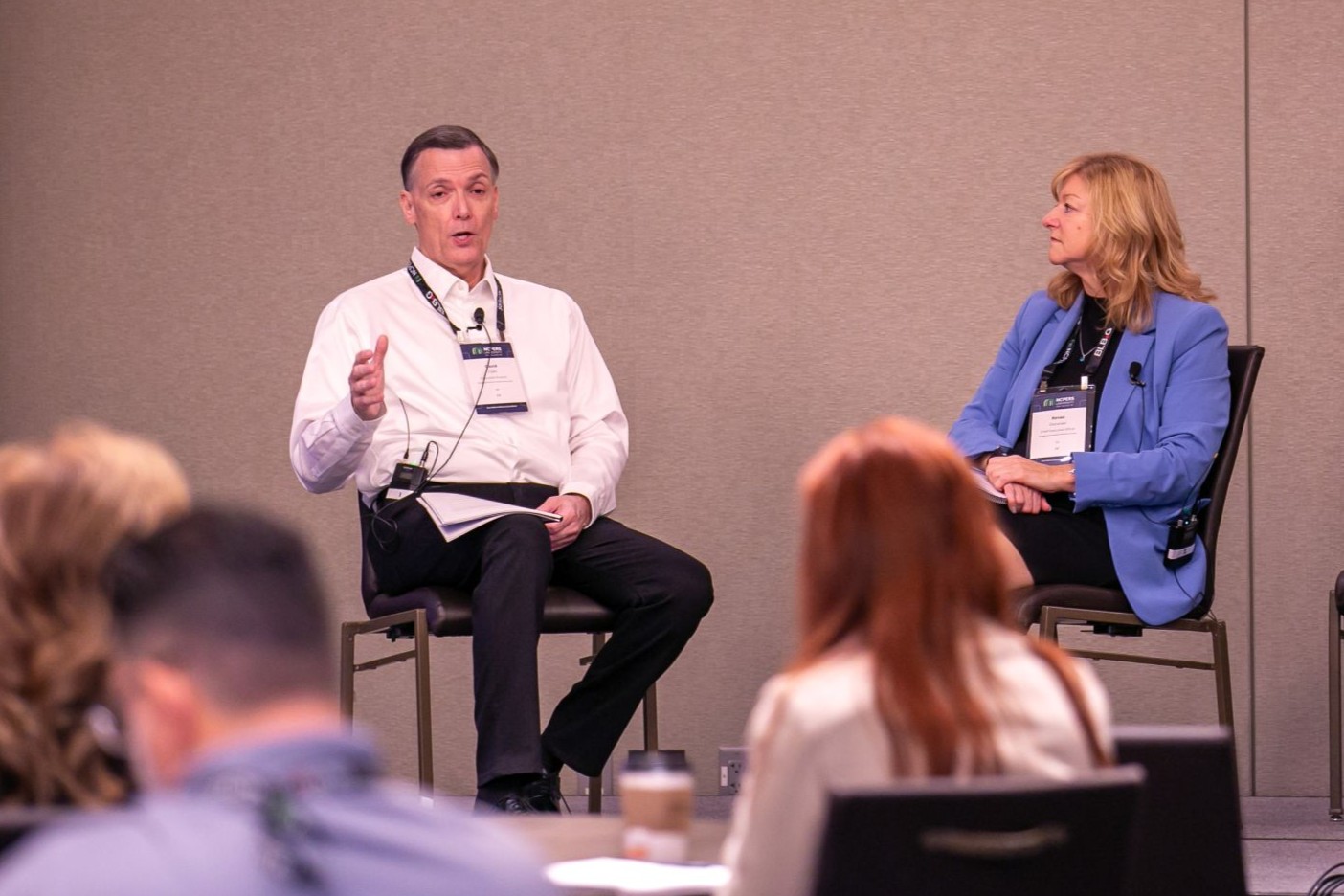 Two presenters sitting on stage giving a presentation
