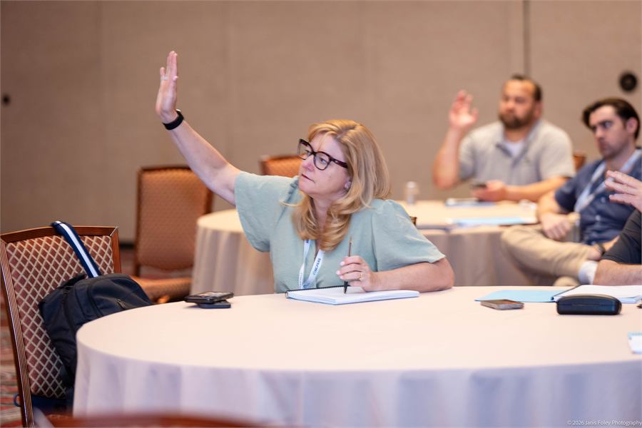 Attendees raising their hands to ask a question
