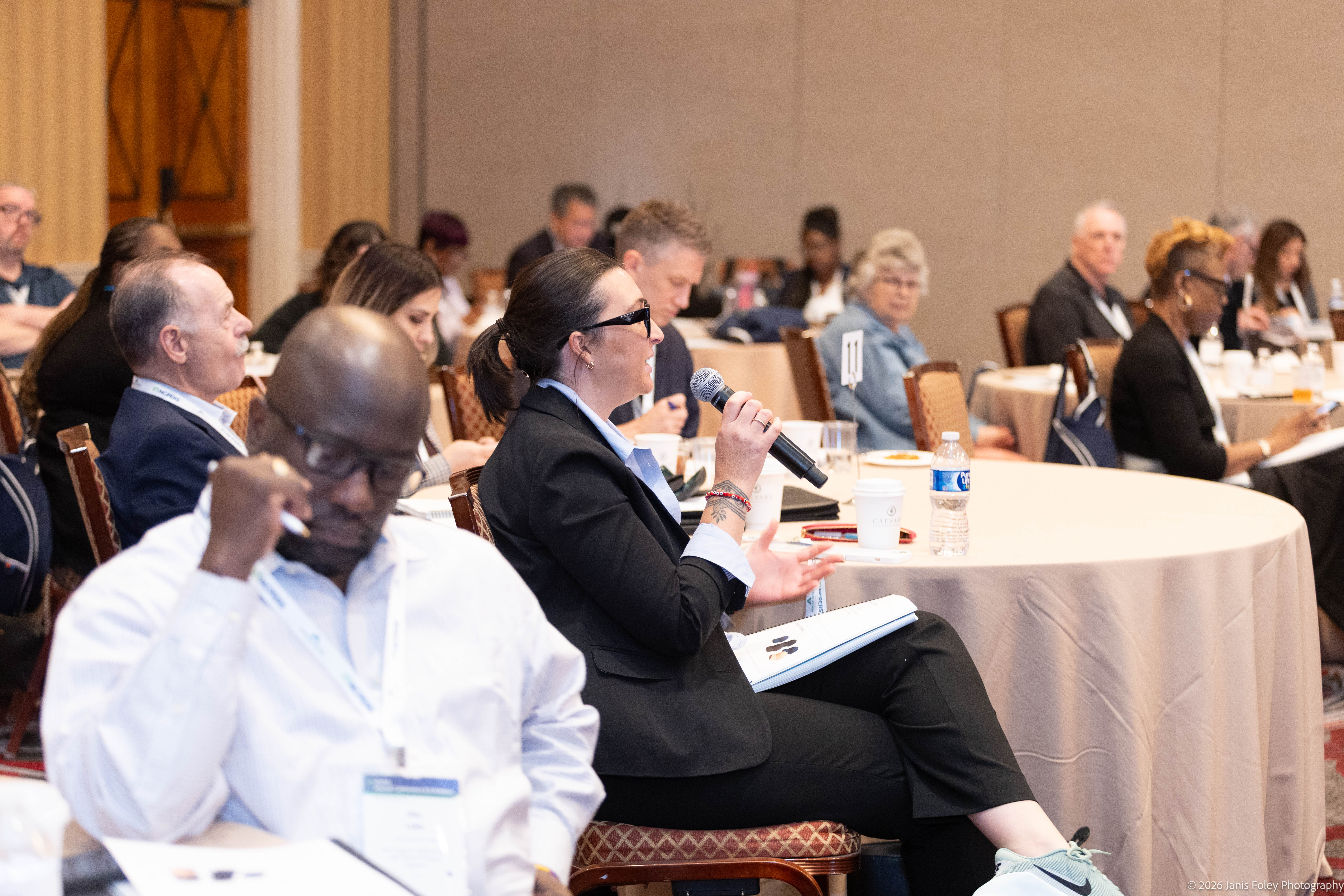 An attendee asks a question with a handheld microphone during a Trustee Essentials Training session