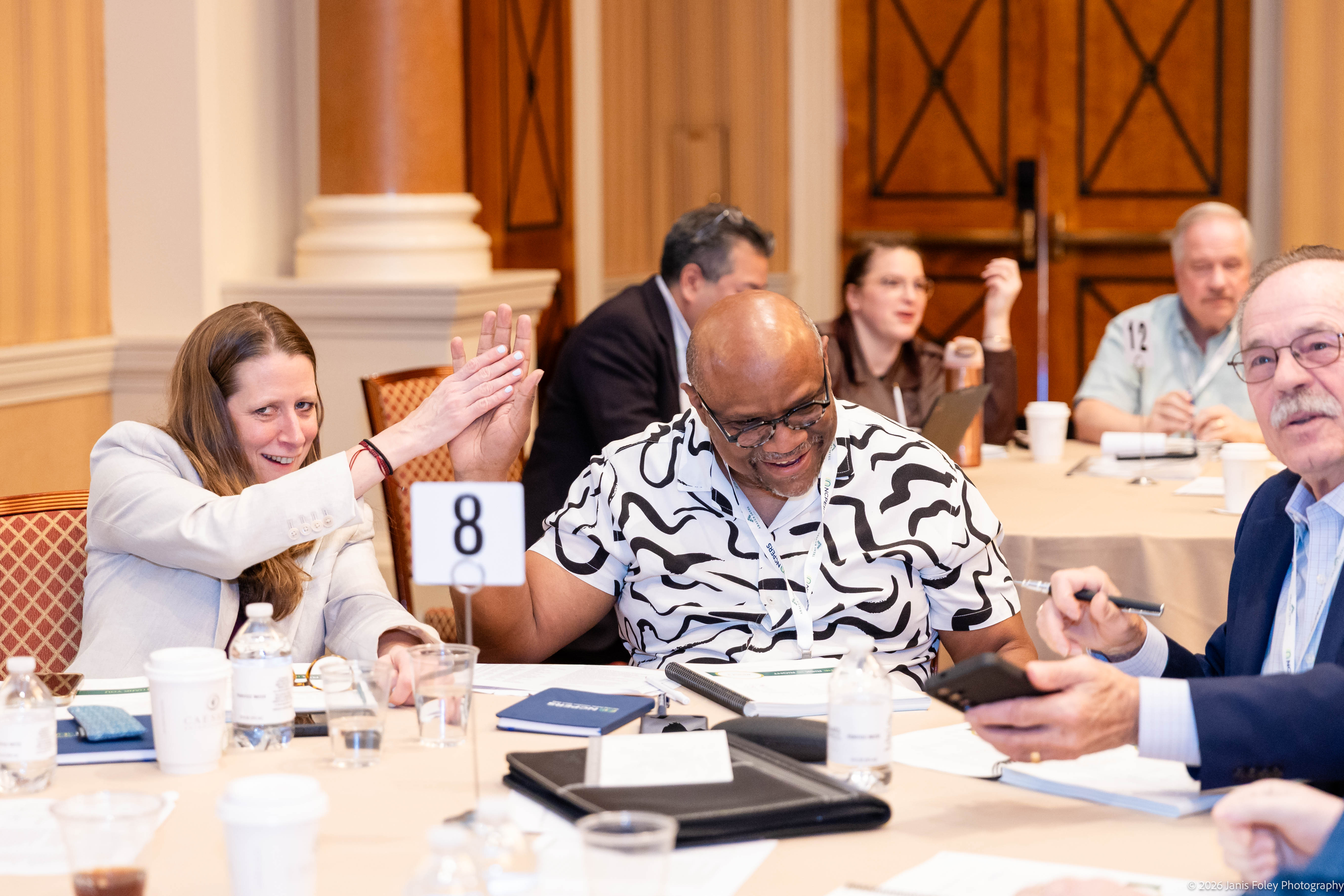 Two attendees high-five at their table during a Trustee Essentials Training group exercise