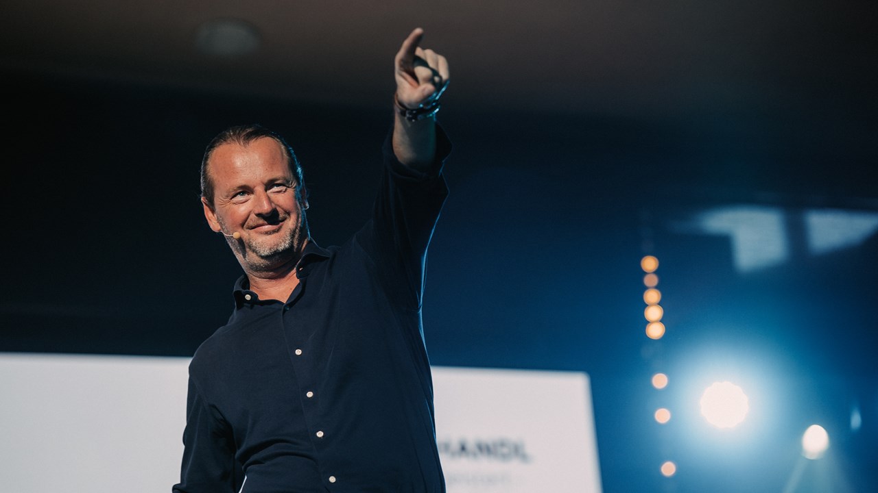 Gabriel Schandl delivers his closing keynote to over 1,000 people, smiling and pointing upward.