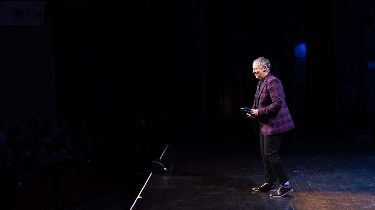 Amy laughing with the audience while emceeing TEDx Asheville 2026