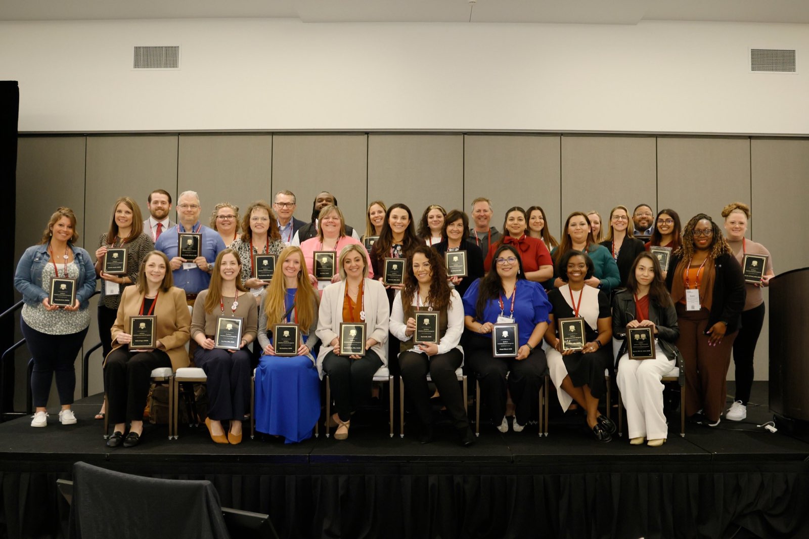 Newly certified graduates holding their plaques at the Patient Access Collaborative Symposium