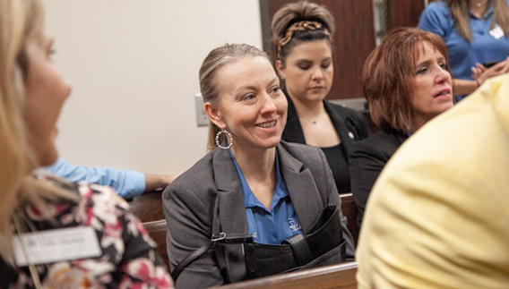 Woman smiling in crowd watching a presentation