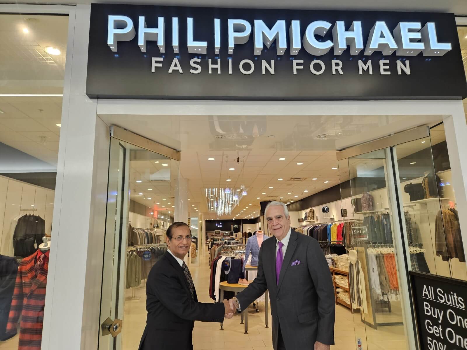 Phil Scotti and Bishan Dass shaking hands in front of Philip Michael Fashion for Men store