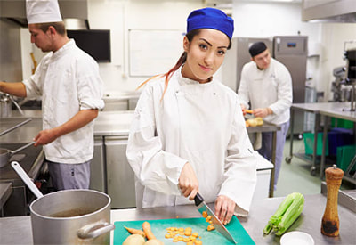 A student prepares food in a commercial kitchen
