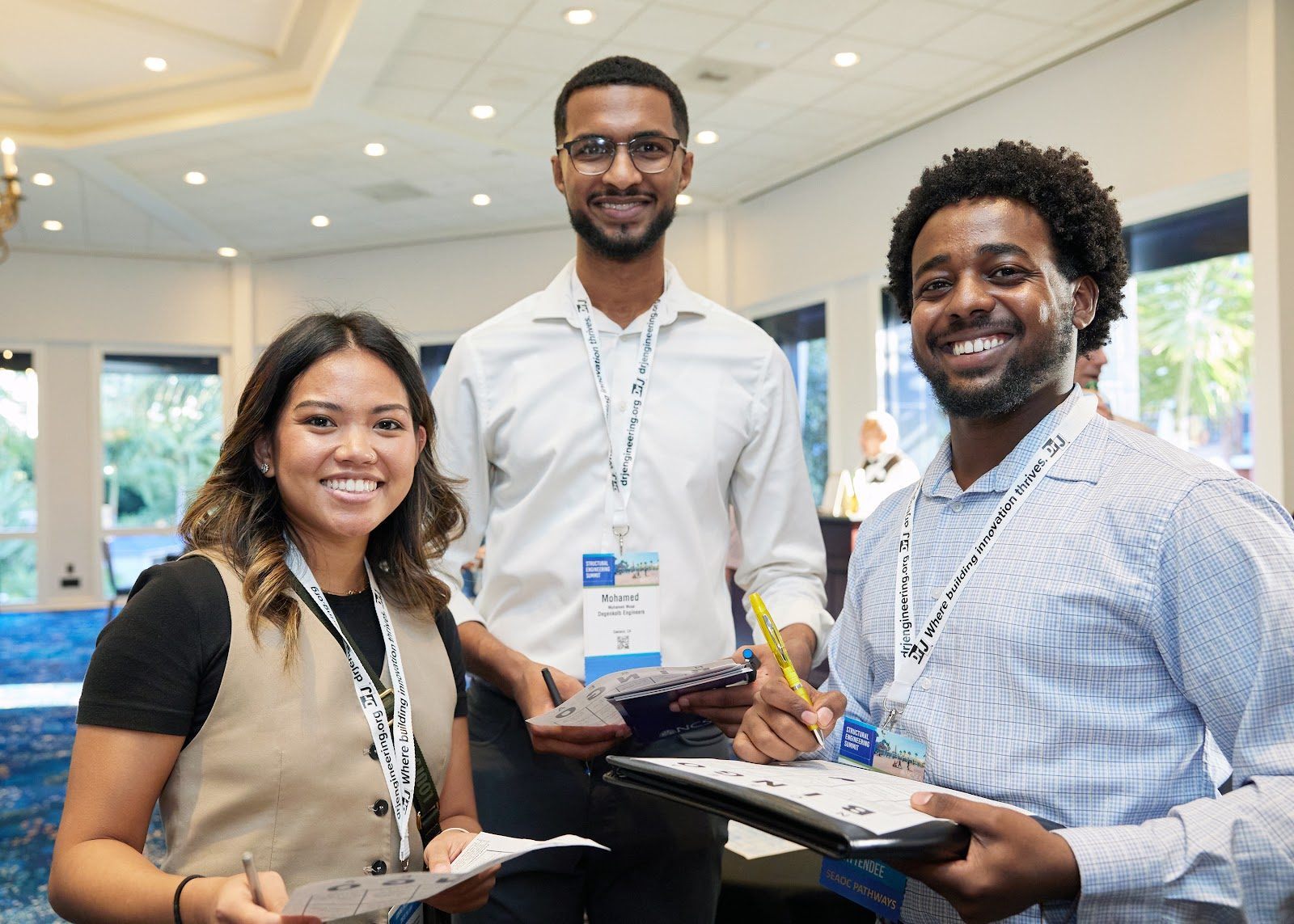 Three smiling SE Pathways cohort members holding workshop materials at a SEAOC event
