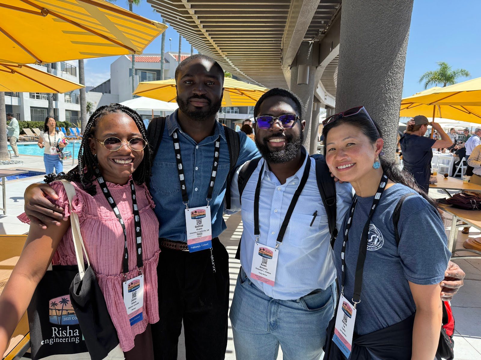 Four cohort members with arms around each other outdoors at a convention