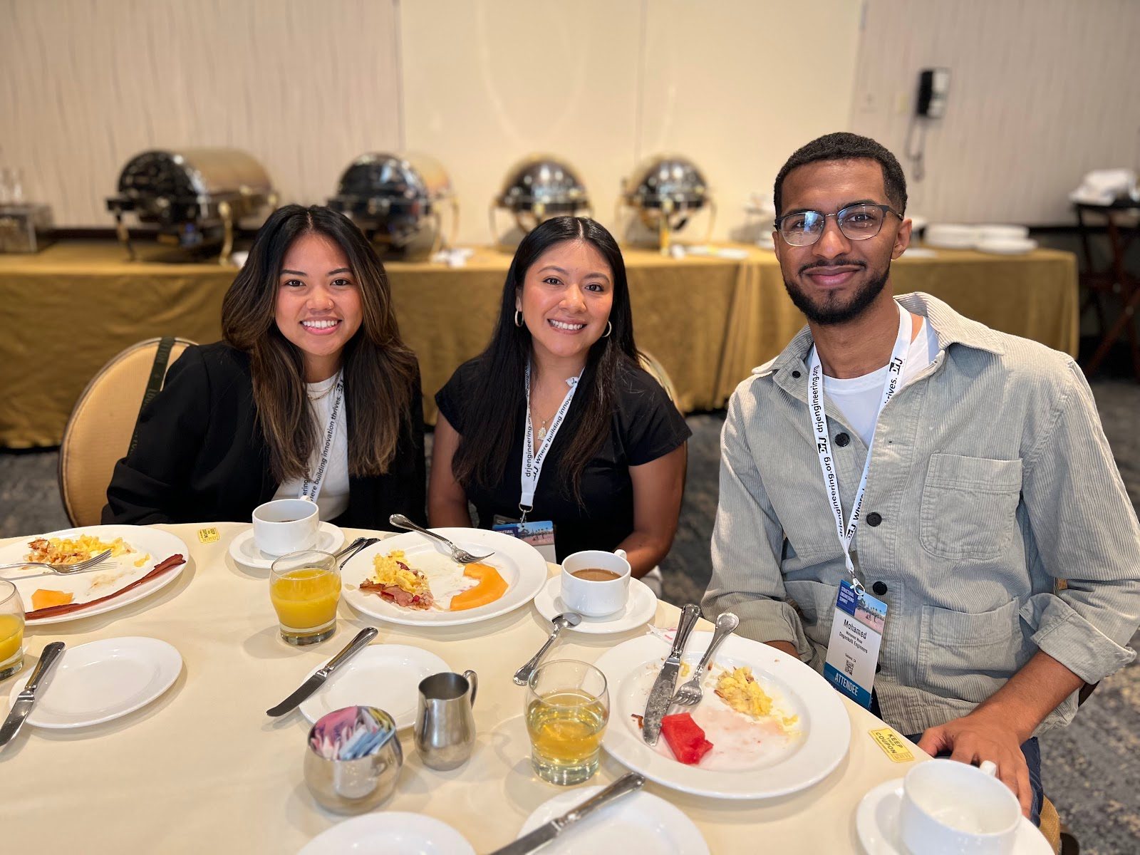 Three cohort members smiling at a breakfast table